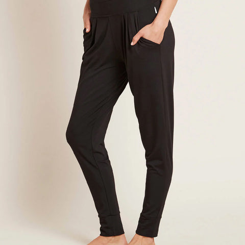 A model wearing black, lightweight lounge pants made of organic bamboo, featuring a draped fit with a wide waistband, tapered leg and two side pockets, showing the side.