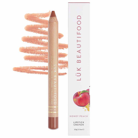 A light warm nude lipstick crayon, placed on a swatch of its color and texture, next to its packaging.