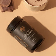 Superfeast Mason's Mushrooms bottle lying on it's side on a beige surface with a coffee cup off to the side.