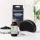 Holistic Hair Herbal Detangling Rinse bottle with its packaging box, a black detangling brush, and scattered black hair caps on a white surface with white flowers in the background.