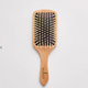 Wooden hairbrush with bristle head on a light grey background.