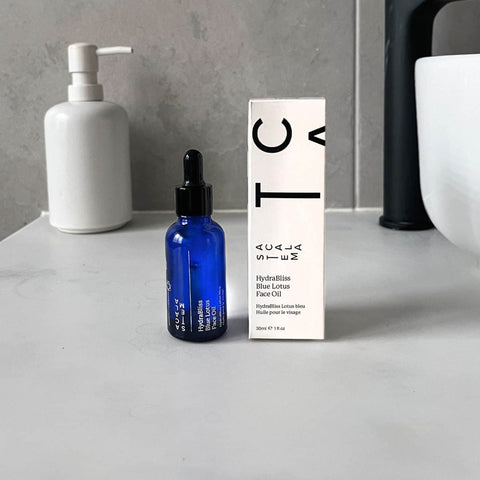 Blue bottle of facial oil with a white box on a grey bathroom vanity.
