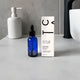 Blue bottle of facial oil with a white box on a grey bathroom vanity.