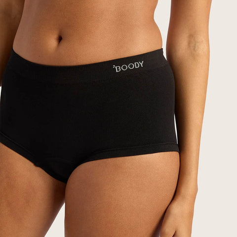A close-up of a model wearing black high-waisted briefs with the brand name 'BOODY' printed in white on the front waistband, set against a light grey studio background.