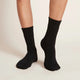Black socks worn by a person on a plain background