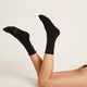 Black socks worn by a person on a plain background