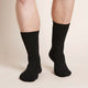 Black crew boot socks worn by a man on a beige background
