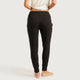 Rear view of a model wearing black high-waisted lounge pants with side pockets, paired with a white cropped top, against a pale studio background.