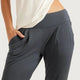 Close-up of a person wearing dark slate grey (storm) lounge pants with a wide elastic waistband and side pockets, paired with a cream-coloured top against a light grey background.