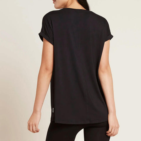 A model wearing a black, lightweight lounge top made of organic bamboo, featuring a softly curved neckline, back seam detail and a subtle curved high-to-low-hem, showing the back.
