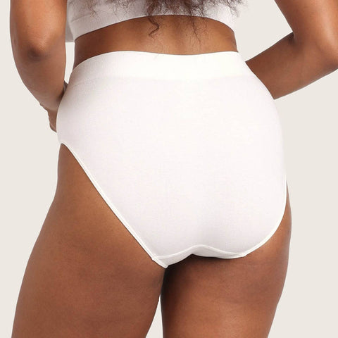 Rear view of a model wearing high-waisted white briefs against a light beige studio background.