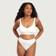A woman modeling a white Boody g-string and crop bra against a solid light grey background.