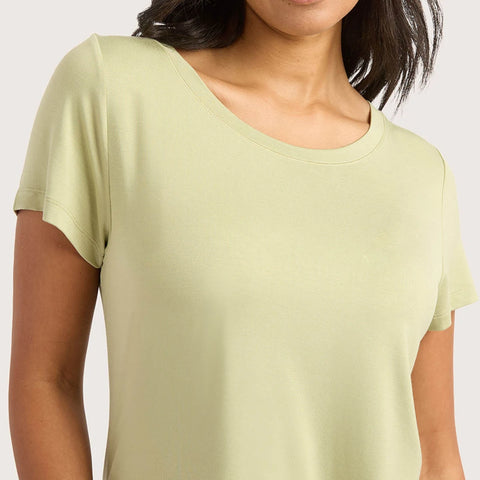A woman wearing a pale sage green short-sleeve crewneck t-shirt, shown from the chest up against a light gray background.