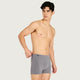 A shirtless male model wearing gray boxer briefs, standing against a light gray studio background.