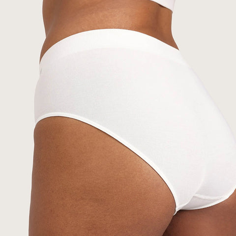 White high-waisted briefs worn by a model, shown from a side-back angle against a light beige studio background.