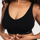 A close-up of a woman wearing a black ribbed scoop-neck sports bra with the brand name 'boody' printed in white on the bottom right band.