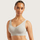 A woman wearing a light heather gray scoop-neck bralette with a ribbed underband, featuring the 'BOODY' brand name on the front, set against a solid light gray background.