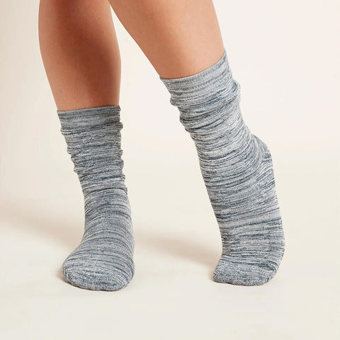A pair of chunky bed socks for women in a dove marl, grey colour modelled on feet.