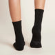 A pair of black, women's crew boot socks modelled on feet, showing the soles.