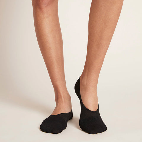 Black no-show socks worn by a model standing against a neutral background