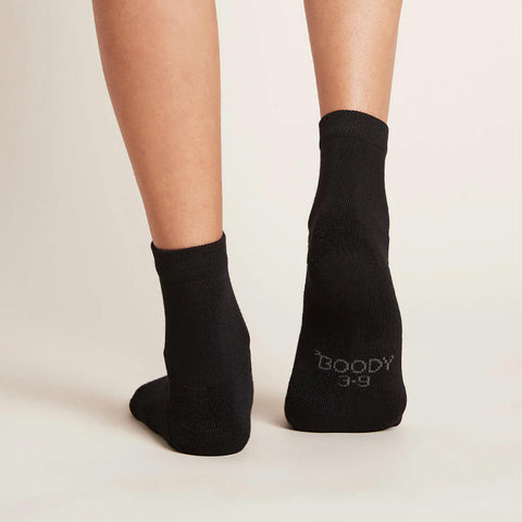 A pair of black, women's quarter crew socks modelled on feet, showing the soles.
