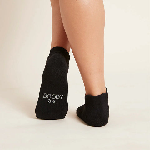 A pair of black sports ankle socks modelled on feet, showing the soles.
