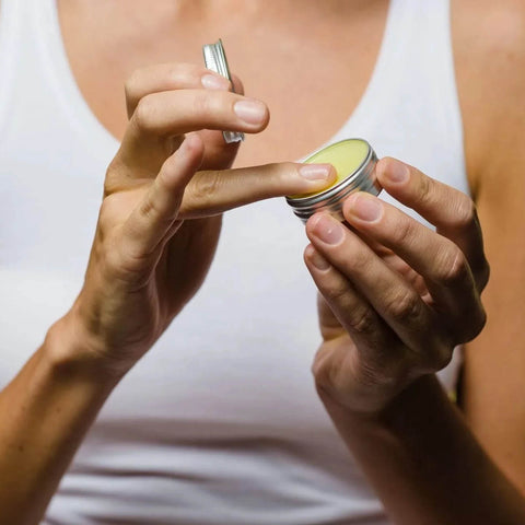 Person applying a small container of healing lip balm to their finger