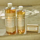 Two bottles and a bar of Dr. Bronner's Pure-Castile Magic Soap - Sandalwood Jasmine scented on a textured surface.