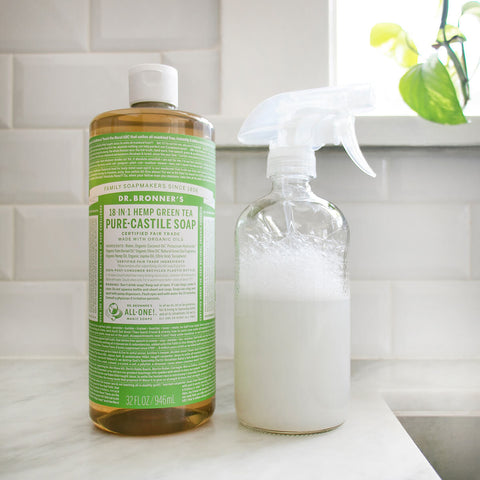 Bottle of Dr. Bronner's 18-In-1 Pure Castile Soap next to a spray bottle on a counter.
