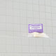 Bar of soap with a purple label on a tiled bathroom wall