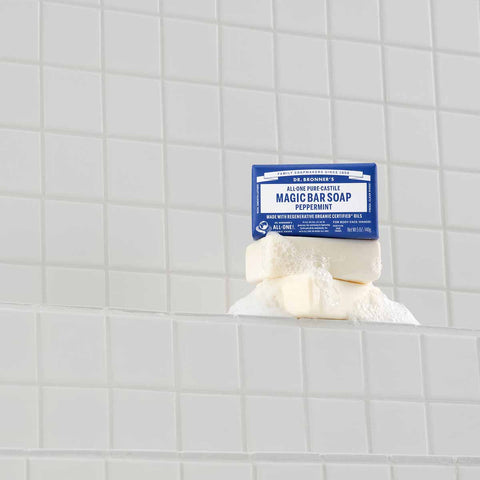 Bar of peppermint magic soap with a blue label on a tiled bathroom wall