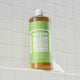Bottle of Dr. Bronner's Magic Soap Green Tea on a tiled shower wall.