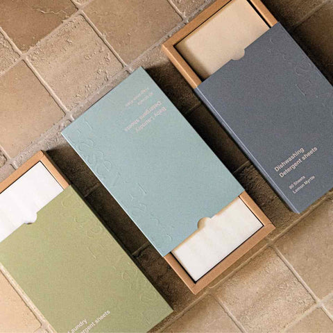 Three open boxes of detergent sheets on a tiled surface.