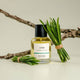 Bottle of ECO. Modern Essentials Lyon 50ml perfume with green leaves & a branch on a light background.