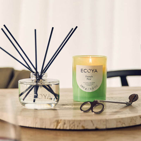 ECOYA French Pear candle and diffuser set on a table with a blurred background.