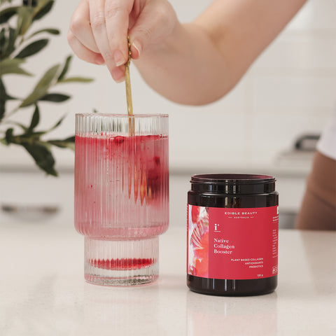 Edible Beauty's Native Collagen Booster, a plant based natural collagen booster powder containing a complex of amino acids, vitamin C and antioxidants being stirred in a glass of water.