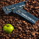 Two 'eimele Pro-TABOLISM PLUS' packets on coffee beans with a green apple.