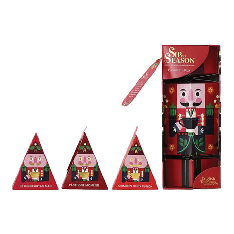 A Christmas-themed tea gift set featuring a red box alongside three pyramid-shaped tea bags.