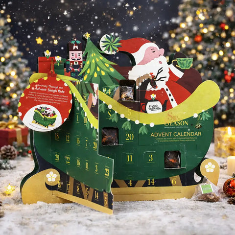 A festive Christmas advent calendar shaped like a sleigh, decorated with green panels, numbered doors, a Santa Claus figure, a tree, and holiday ornaments, set in a snowy scene.