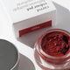 Red carrot colour pot in a jar with a white box labelled 'Happy' on a light background
