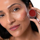 Woman with a close-up of happy colour pot and product on both her cheeks & lips.