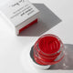 Bright red carrot colour pot in the shade 'hello'. White packaging & aluminium lid.
