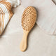Bamboo hair brush styled on a counter with a towel.