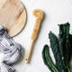 Bottle brush styled on a kitchen bench with cutting board, kale & a striped linen towel.