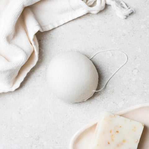 Original konjac sponge pictured on a bathroom surface next to a face towel.