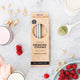 Packaging of silicone drinking straws with a cleaning brush on a kitchen surface with smoothie ingredients scattered around.