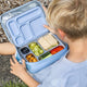 Child sitting in the grass with his lunch bag containing the Ever Eco stainless steel bento lunch box with snacks & sandwiches in each of the compartments.