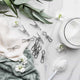 Ever eco clothes pegs styled with some textured towels on a marble surface with some laundry powder in a glass container & some decorative leaves & flowers.