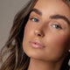 Close-up of a woman's face with a neutral background. Wearing Eye of Horus Brow Fibre Extend Dynasty.