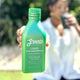 Green bottle of Liquid Chlorophyll held by a person with a blurred background.
